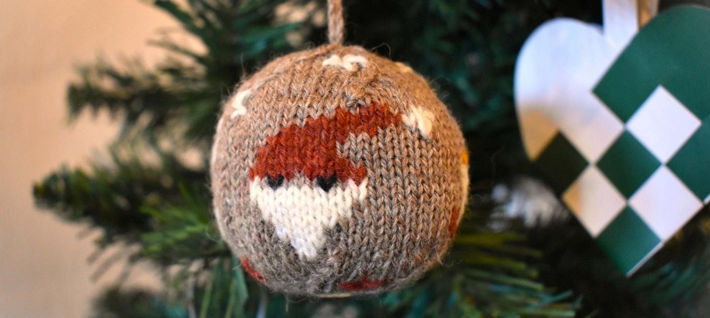 Die Weihnachtskugel 2024 ist aus Bio-Garn gestrickt und mit vier Weihnachtsmotiven versehen