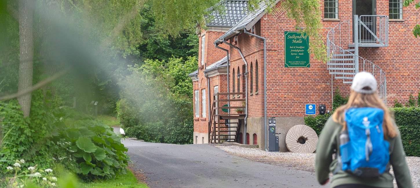 Ein Wanderer geht an der malerischen Sulkendrup-Mühle vorbei