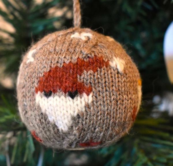 Die Weihnachtskugel 2024 ist aus Bio-Garn gestrickt und mit vier Weihnachtsmotiven versehen