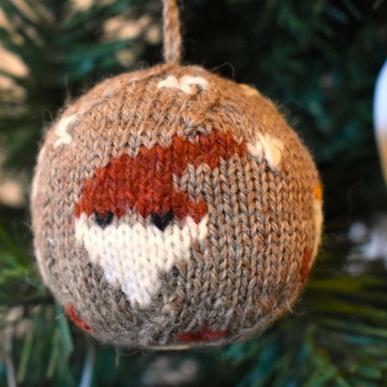 Die Weihnachtskugel 2024 ist aus Bio-Garn gestrickt und mit vier Weihnachtsmotiven versehen