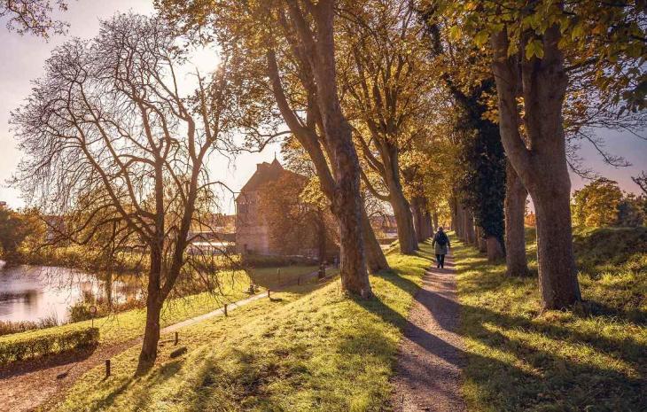 En turist går på Nyborg Vold i det flotteste efterårsvejr